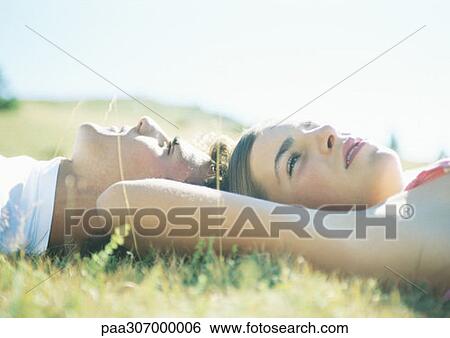 Teenage couple lying on grass, head to head View Large Photo Image Stock Photograph - Teenage couple lying on grass, head to head. Fotosearch