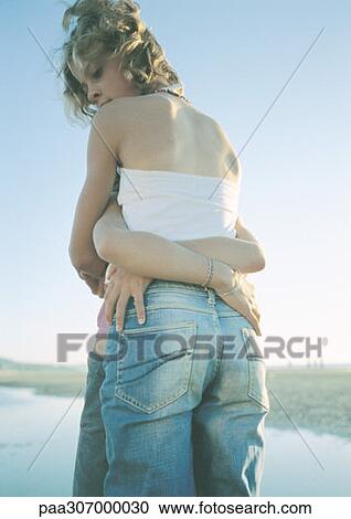Stock Image - Two children standing on beach, embracing. Fotosearch