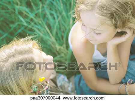 Two girls sitting in grass, talking View Large Photo Image Picture - Two girls sitting in grass, talking. Fotosearch