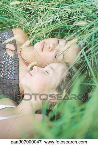 Two girls sleeping in grass View Large Photo Image Stock Photo - Two girls sleeping in grass. Fotosearch