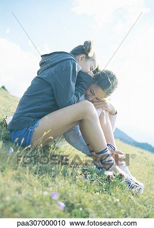 Two girls whispering and sitting on grass together View Large Photo Image Stock Image - Two girls whispering and sitting on grass together. Fotosearch