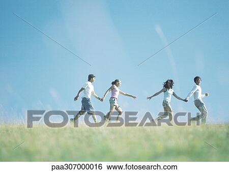 Two young couples walking hand in hand outside, girls reaching for each other's hands View Large Photo Image Stock Photograph - Two young couples walking hand in hand outside, girls reaching for each other's hands. Fotosearch