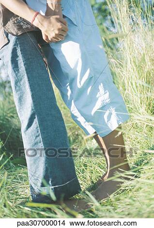 Young couple standing in grass, holding hands View Large Photo Image Picture - Young couple standing in grass, holding hands. Fotosearch