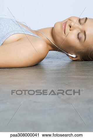 Woman lying on floor, listening to earphones View Large Photo Image Stock Image - Woman lying on floor, listening to earphones. Fotosearch