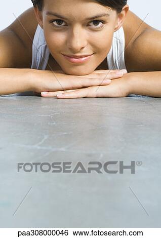 Woman lying on floor, resting head on hands View Large Photo Image Stock Photograph - Woman lying on floor, resting head on hands. Fotosearch