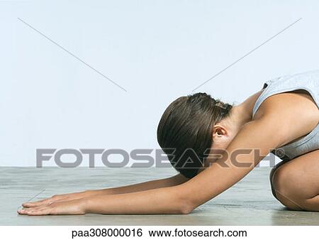 Young woman kneeling on floor, stretching View Large Photo Image Stock Photograph - Young woman kneeling on floor, stretching. Fotosearch