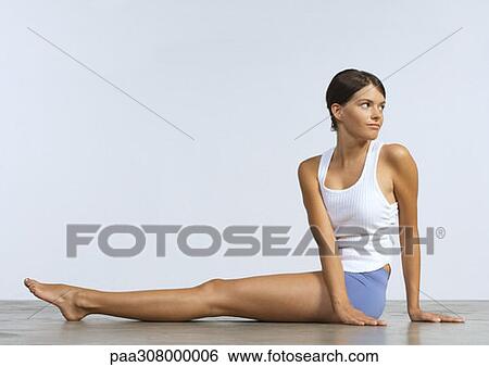 Young woman sitting on floor doing stretches View Large Photo Image Stock Photograph - Young woman sitting on floor doing stretches. Fotosearch