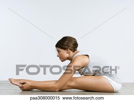 Young woman sitting on floor, stretching View Large Photo Image Stock Photography - Young woman sitting on floor, stretching. Fotosearch