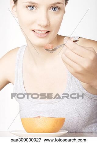 Young woman eating grapefruit View Large Photo Image Stock Photo - Young woman eating grapefruit. Fotosearch