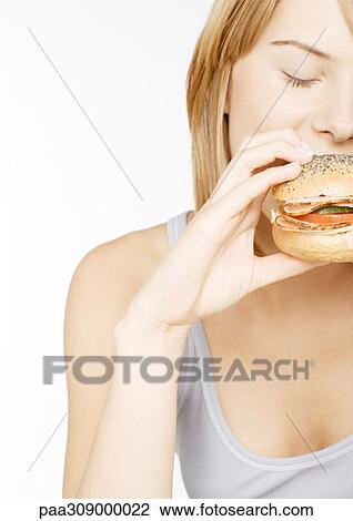 Stock Image - Young woman eating sandwich. Fotosearch