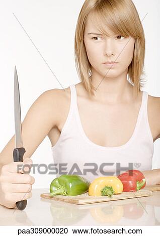 Young woman holding up knife in front of bell peppers View Large Photo Image Stock Image - Young woman holding up knife in front of bell peppers. Fotosearch