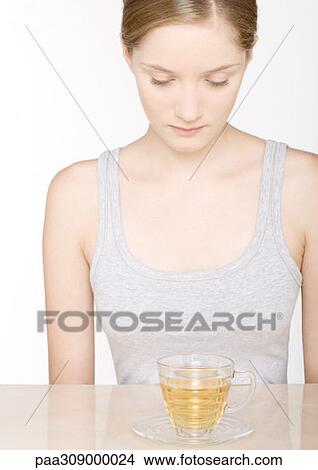 Young woman looking down at herbal tea View Large Photo Image Picture - Young woman looking down at herbal tea. Fotosearch