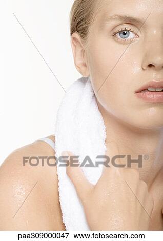 Stock Photo - Young woman perspiring, with towel around neck. Fotosearch