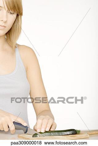 Stock Photo - Young woman slicing zucchini. Fotosearch