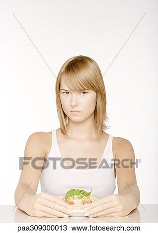 Stock Image - Young woman with arms around plate of pasta. Fotosearch