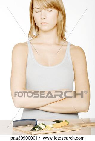 Young woman with arms folded looking down at sliced zucchini View Large Photo Image Stock Photo - Young woman with arms folded looking down at sliced zucchini. Fotosearch
