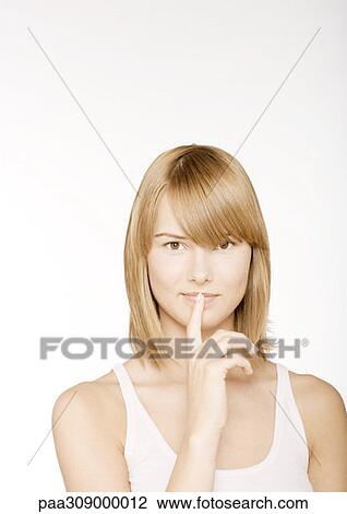 Young woman with finger in front of lips View Large Photo Image Stock Image - Young woman with finger in front of lips. Fotosearch