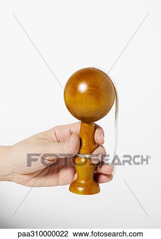 Stock Image - Hand holding wooden cup and ball toy. Fotosearch