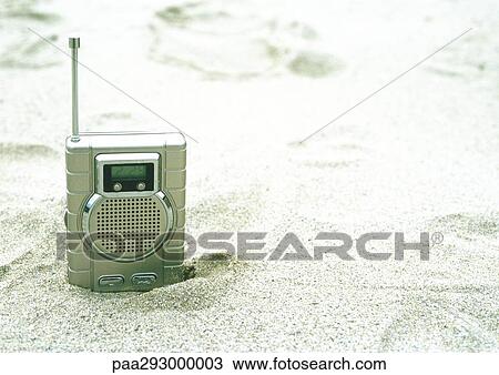 Stock Image - Radio sticking out of sand on beach. Fotosearch