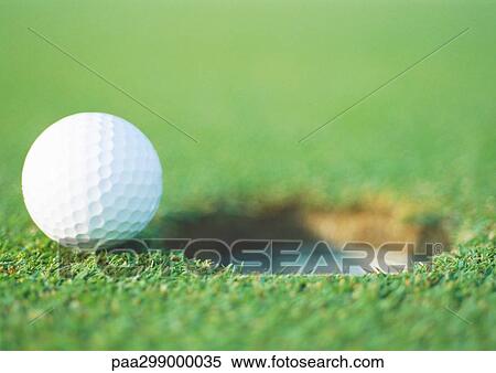 Golf ball at edge of hole, close-up View Large Photo Image Stock Photography - Golf ball at edge of hole, close-up. Fotosearch