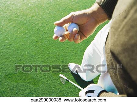 Stock Photo - Golfer holding golf balls, high angle view. Fotosearch
