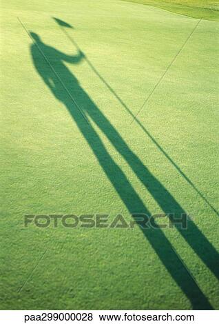 Stock Photo - Shadow of golfer holding golf flag. Fotosearch