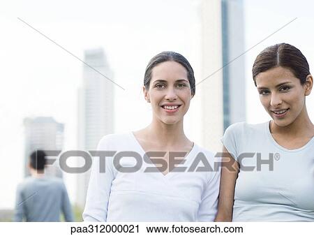 Two young woman, side by side in urban setting View Large Photo Image Stock Image - Two young woman, side by side in urban setting. Fotosearch