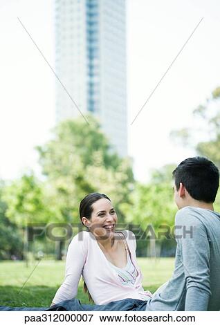 Young couple sitting in urban park View Large Photo Image Stock Photo - Young couple sitting in urban park. Fotosearch