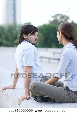 Young couple sitting in urban park View Large Photo Image Stock Photo - Young couple sitting in urban park. Fotosearch