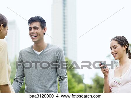 Young man and two young women in urban park View Large Photo Image Picture - Young man and two young women in urban park. Fotosearch