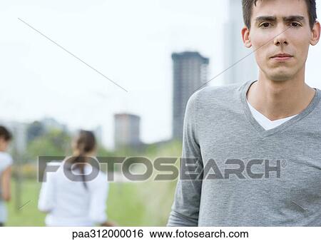 Young man frowning in urban park View Large Photo Image Stock Photograph - Young man frowning in urban park. Fotosearch