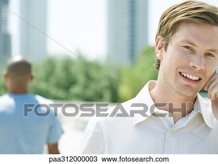 Young man using cell phone in urban park View Large Photo Image Stock Image - Young man using cell phone in urban park. Fotosearch