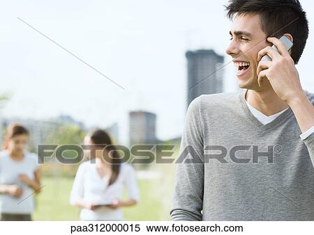 Young man using cell phone in urban park View Large Photo Image Stock Photography - Young man using cell phone in urban park. Fotosearch