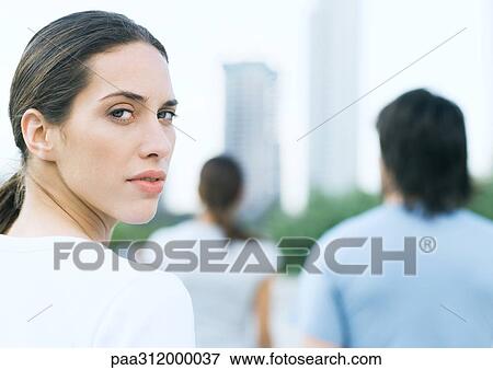 Young woman looking over shoulder in urban park View Large Photo Image Stock Photo - Young woman looking over shoulder in urban park. Fotosearch