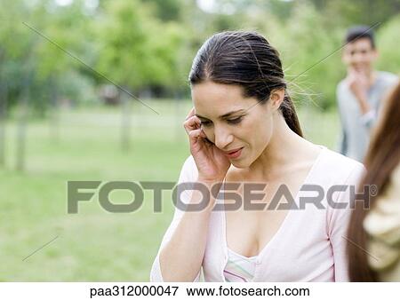 Stock Photo - Young woman using cell phone in park. Fotosearch
