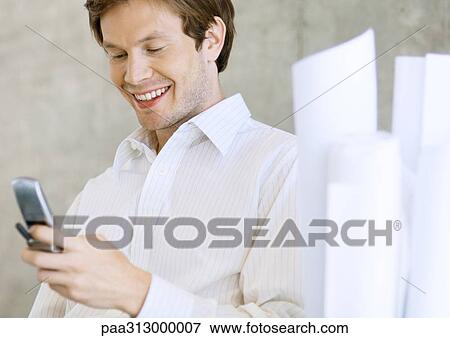 Architect holding cell phone, smiling View Large Photo Image Stock Photo - Architect holding cell phone, smiling. Fotosearch