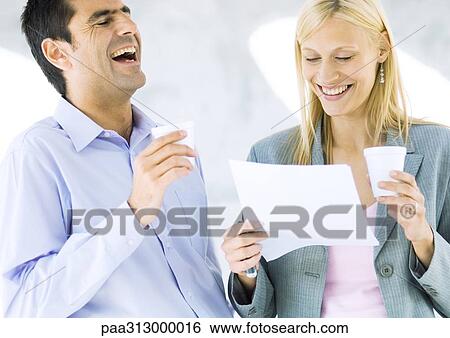 Businessman and businesswoman holding cups and laughing over document View Large Photo Image Stock Photograph - Businessman and businesswoman holding cups and laughing over document. Fotosearch