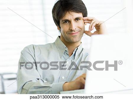 Man sitting at laptop, smiling View Large Photo Image Stock Photography - Man sitting at laptop, smiling. Fotosearch