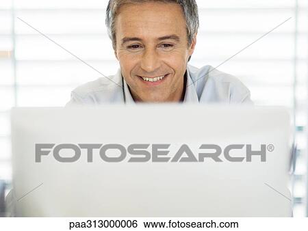 Stock Photograph - Middle-aged man using laptop. Fotosearch
