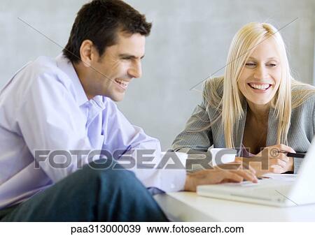 Two business colleagues using laptop and laughing View Large Photo Image Stock Photo - Two business colleagues using laptop and laughing. Fotosearch