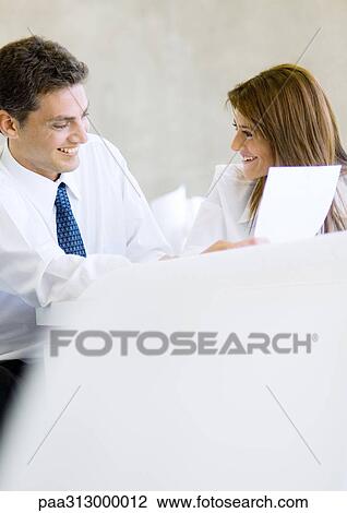 Stock Image - Two business colleagues working together and laughing. Fotosearch