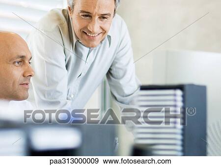 Two businessmen working in office together View Large Photo Image Stock Photo - Two businessmen working in office together. Fotosearch