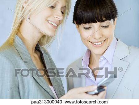 Two businesswomen looking at cell phone View Large Photo Image Stock Image - Two businesswomen looking at cell phone. Fotosearch