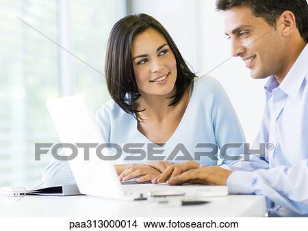 Woman and man working on laptop together View Large Photo Image Picture - Woman and man working on laptop together. Fotosearch