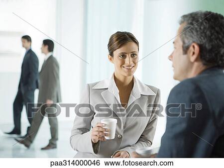 Stock Photograph - Business colleagues having coffee break in lobby. Fotosearch