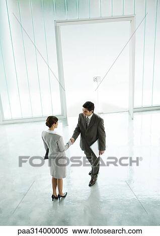 Stock Photography - Businessman and businesswoman shaking hands in lobby. Fotosearch