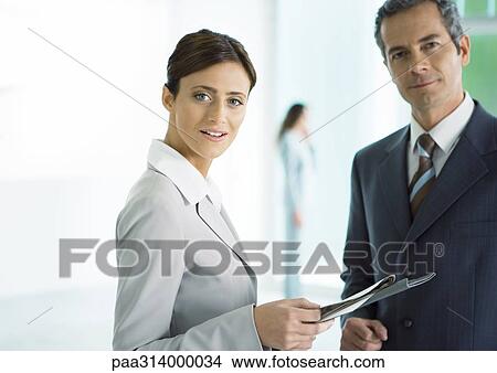 Picture - Businessman and businesswoman standing with file. Fotosearch
