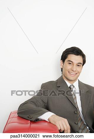 Businessman sitting on couch, smiling View Large Photo Image Stock Image - Businessman sitting on couch, smiling. Fotosearch
