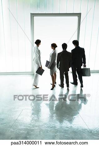 Stock Image - Businesspeople standing near doorway in lobby. Fotosearch