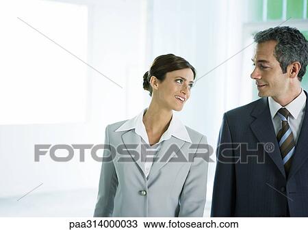 Stock Image - Businesswoman smiling at male colleague. Fotosearch